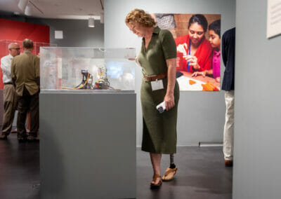 Adult with prosthetic leg viewing prosthetic artifacts from Bespoke Bodies exhibition.