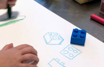 Child does orthographic drawings of a blue Lego.