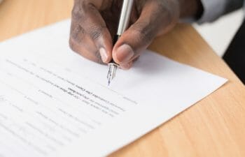 A close up of a hand signing a document with a fountain pen