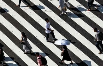 Crowd of people walking against black and white striped background.