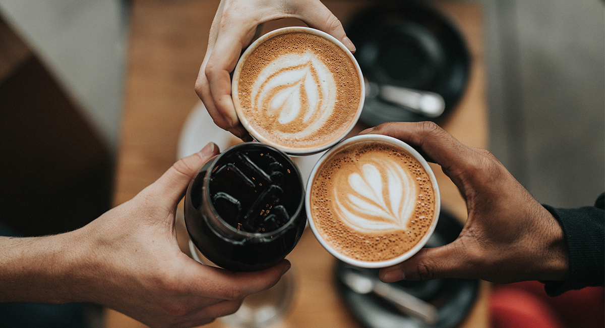 Photo of a group of people having coffee. Overhead view of coffee cups with coffee art.