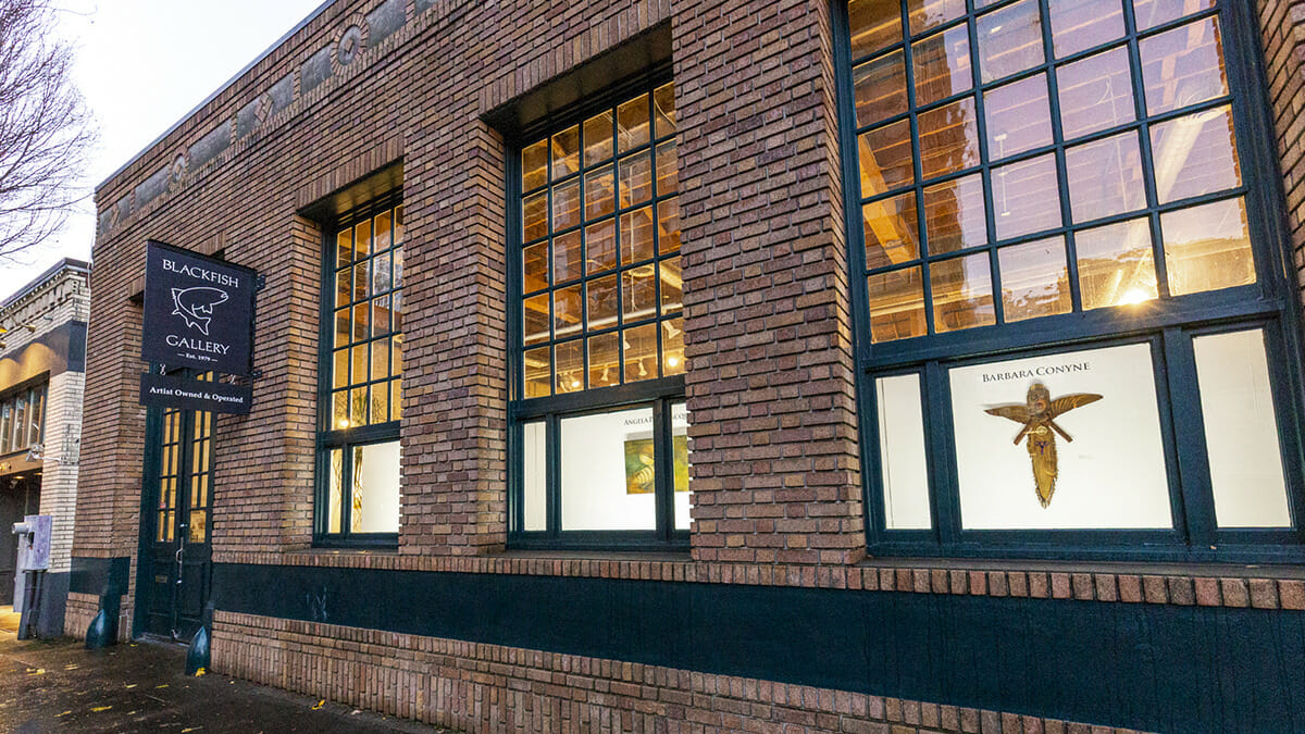 Exterior view of Blackfish Gallery with tall windows showing art on display.