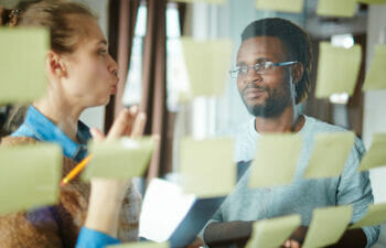 Two adults working on a project with sticky notes organizing their ideas.