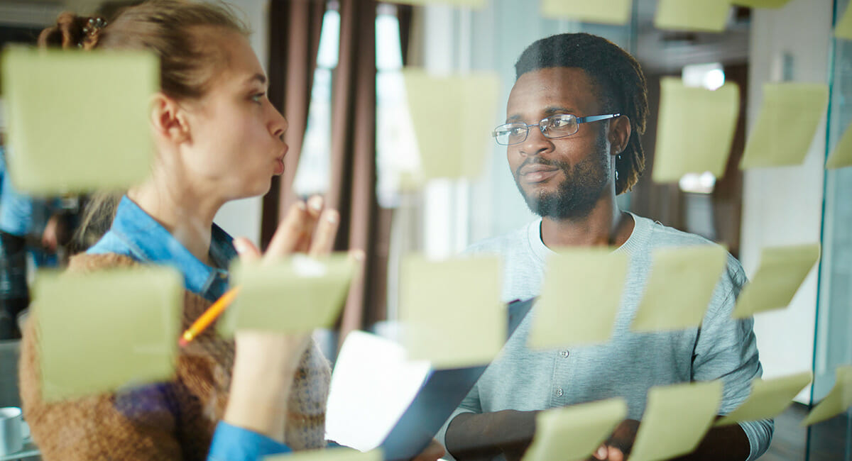 Two adults working on a project with sticky notes organizing their ideas.