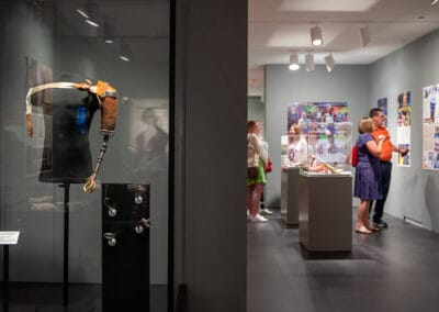 Steampunk Style Arm on display with four attachments and exhibition attendees viewing panels in the background.