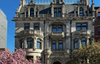 Historic stone multi-story stone building framed by trees in blossom