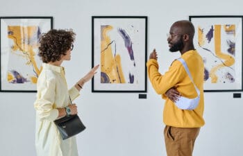 Two people standing in front of and discussing visual artwork in a gallery setting