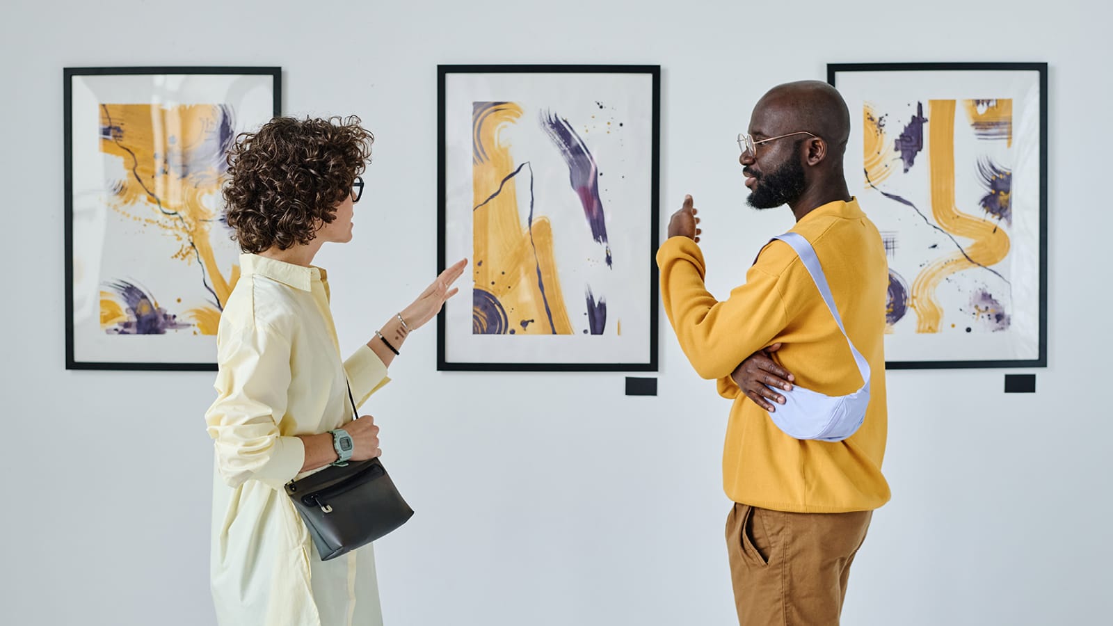 Two people standing in front of and discussing visual artwork in a gallery setting