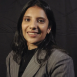 Southeast Asian woman with dark hair wearing a grey and white striped blazer and a black shirt