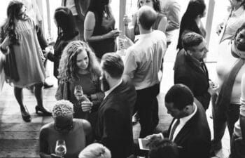 A group of design professionals gathered in a dimly lit, atmospheric venue, engaged in casual conversation.